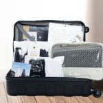 Checklist perlengkapan umroh wanita 2026 tersusun rapi di dalam koper - gamis, bergo, dan travel pouch L.tru