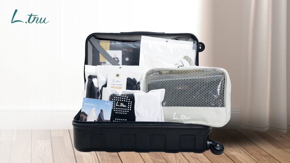 Checklist perlengkapan umroh wanita 2026 tersusun rapi di dalam koper - gamis, bergo, dan travel pouch L.tru